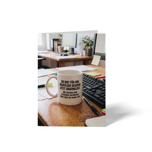 Vorderseite der geschlossenen A6 Abschiedskarte von GHG Supplies. Eine weiße Kaffeetasse auf einem Büroschreibtisch neben einer Tastatur mit dem Spruch Du bist für uns rechtlich gesehen jetzt abgemeldet. Wir werden dich trotzdem vermissen! Alles Gute im neuen Job.