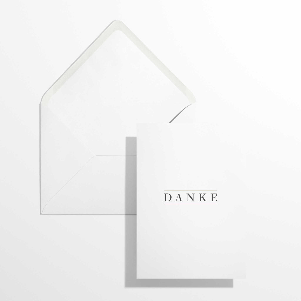 Elegante Dankeskarte Danke im Format B6 flach liegend neben dem geöffneten, naturweißen Premium-Briefumschlag mit klassisch spitzer Verschlussklappe.