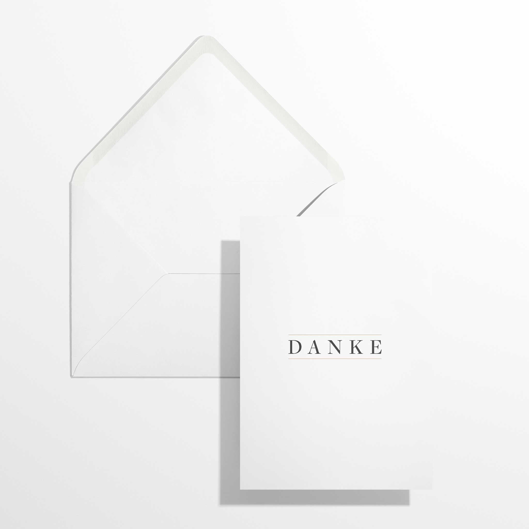 Elegante Dankeskarte Danke im Format B6 flach liegend neben dem geöffneten, naturweißen Premium-Briefumschlag mit klassisch spitzer Verschlussklappe.