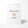 Vorderansicht der hochkant gefalteten B6 Dankeskarte mit einem zentrierten, kreisrunden Goldornament zwischen den schwarzen Schriftzügen HERZLICHEN und DANK.