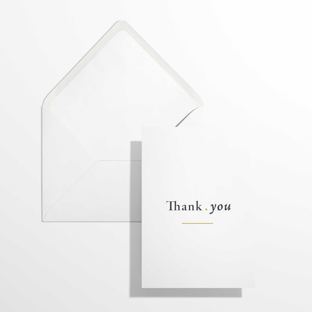 Moderne englische Dankeskarte Thank you im Format B6 flach liegend neben dem geöffneten, naturweißen Premium-Briefumschlag mit klassisch spitzer Verschlussklappe.