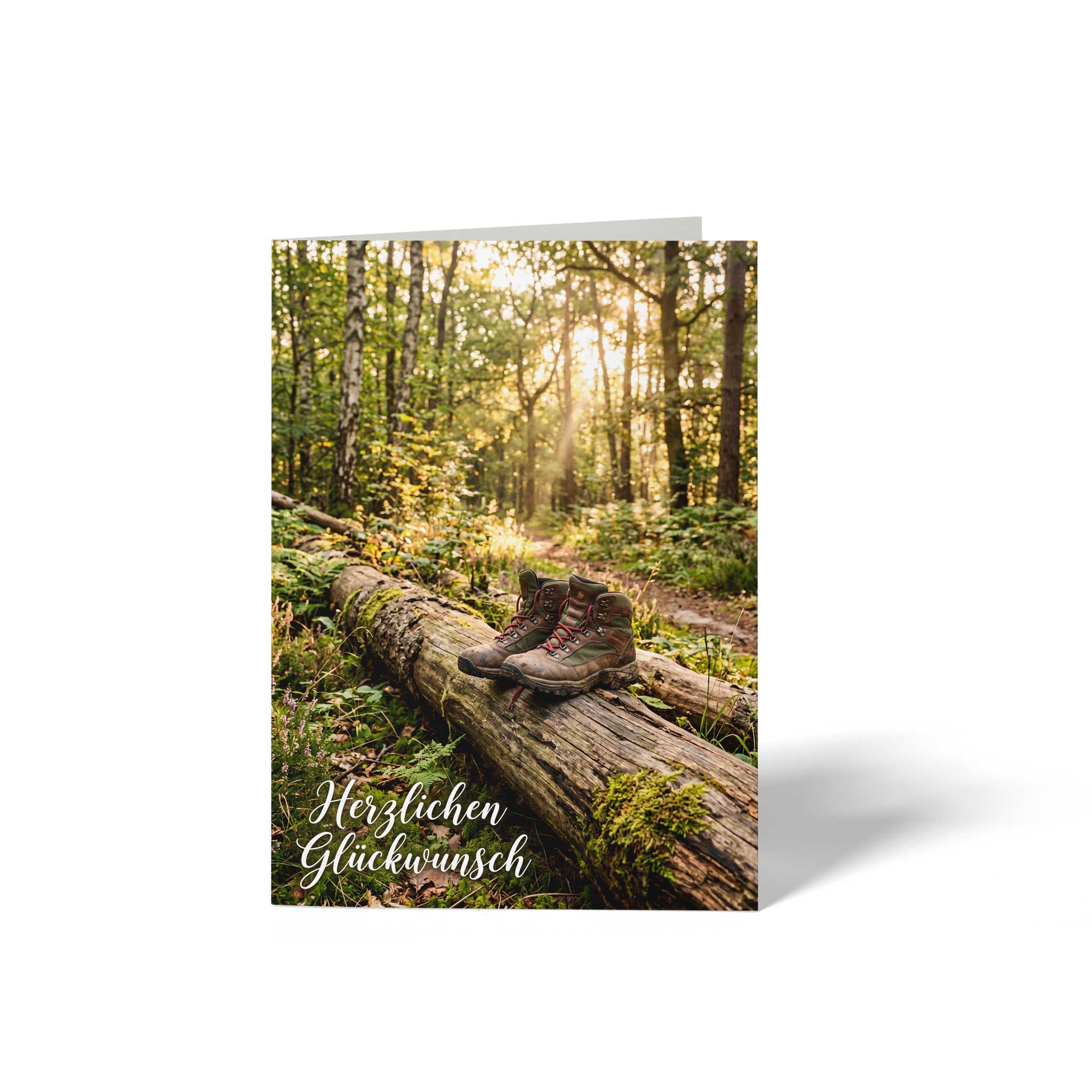 Vorderseite der geschlossenen A6 Glückwunschkarte von GHG Supplies. Ein Paar Wanderschuhe steht auf einem umgestürzten Baumstamm in einem von der Sonne durchfluteten Wald unter dem Text Herzlichen Glückwunsch.