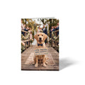 Vorderseite der geschlossenen A6 Hochzeitskarte von GHG Supplies. Ein goldener Labrador-Hund mit blauer Fliege trägt ein Holzschild mit der Aufschrift Meine Menschen haben geheiratet! Alles Liebe von uns allen! vor einer Hochzeitsgesellschaft.