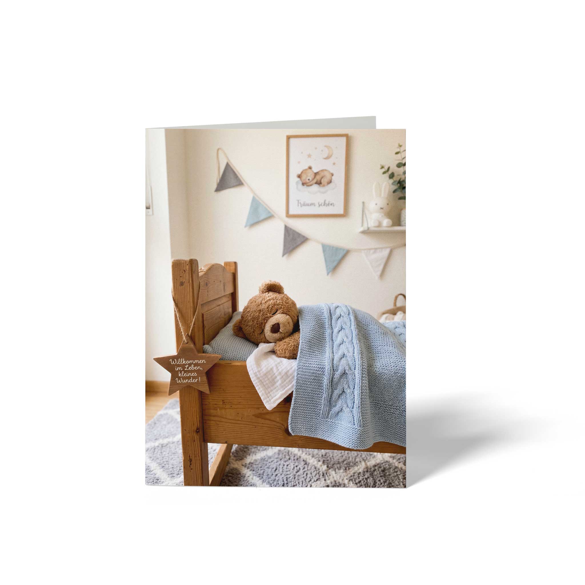 Vorderseite der geschlossenen A6 Glückwunschkarte zur Geburt von GHG Supplies. Schlafender Teddybär im Holzbett unter einer blauen Strickdecke im Kinderzimmer mit Holzstern-Anhänger Willkommen im Leben, kleines Wunder.