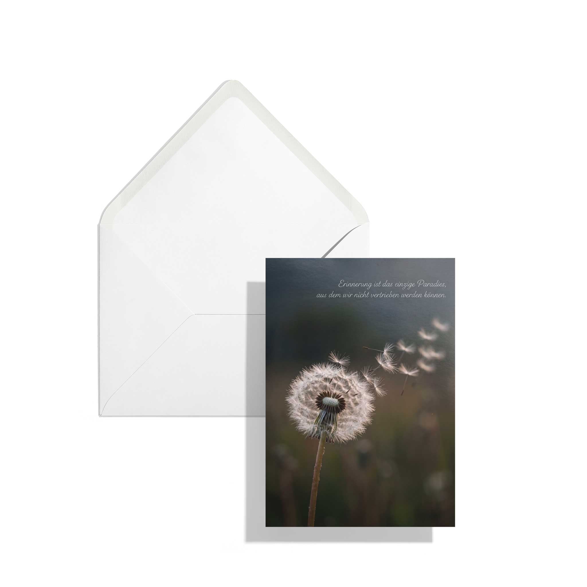 Die hochformatige A6 Kondolenzkarte mit dem Pusteblumen-Motiv liegt leicht versetzt auf einem passenden, klassischen weißen Briefumschlag vor rein weißem Hintergrund.