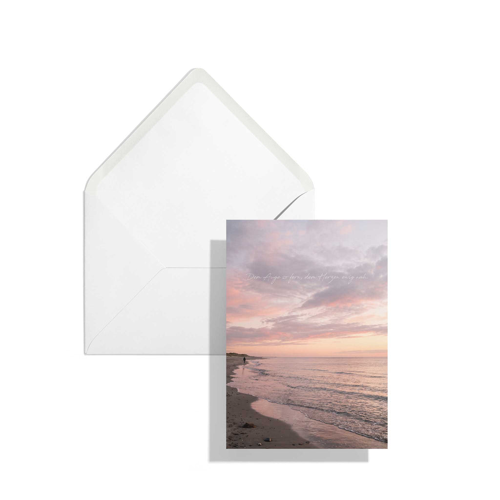 Die hochformatige A6 Kondolenzkarte mit dem Sonnenuntergang-Motiv liegt leicht versetzt auf einem passenden, klassischen weißen Briefumschlag vor rein weißem Hintergrund.