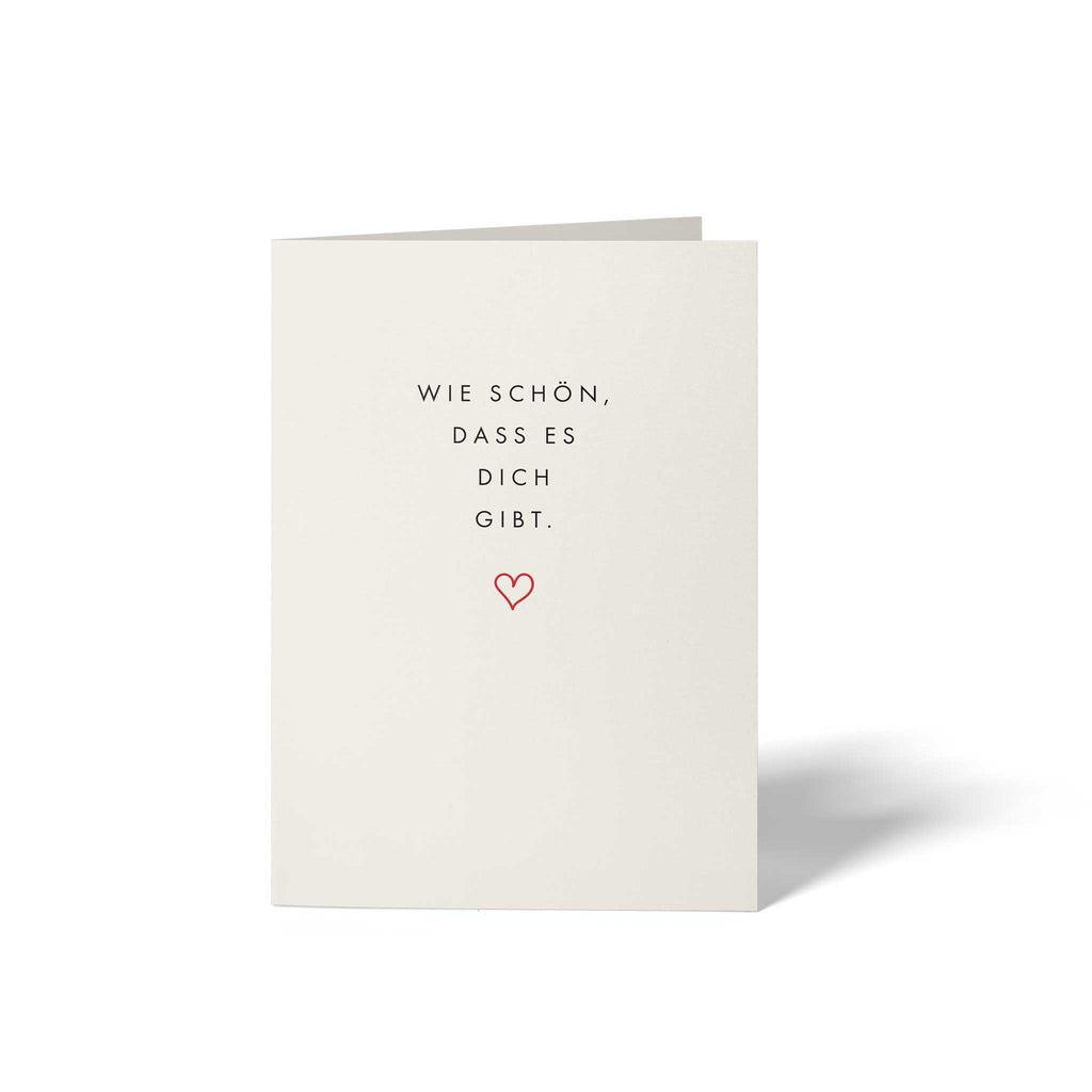 Vorderseite der geschlossenen A6 Glückwunschkarte von GHG Supplies auf edlem Soft-White Olin-Papier mit dem minimalistischen Text Wie schön, dass es dich gibt. und einem kleinen roten Herz.